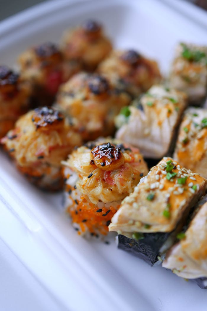 Close-up of assorted sushi rolls with unique toppings and garnishes.